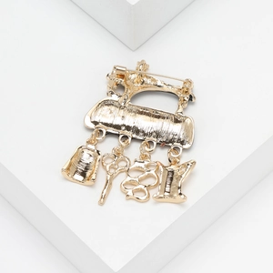 Detail view of a vintage gold sewing machine brooch with dangling scissors and thimble charms