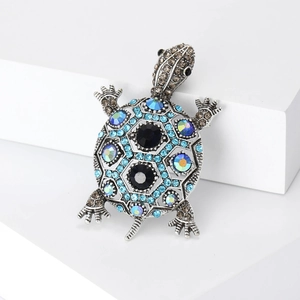 Macro d'une broche tortue vintage en argent avec strass colorés sur bloc blanc