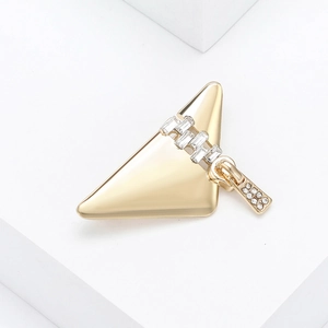 Macro shot of gold triangle brooch with zipper design and sparkling crystal inlay