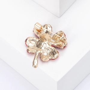 Detail view of the golden metal back of the clover brooch with safety pin fastener
