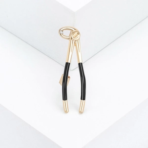 Broche pince dentaire dorée avec manche en émail noir et zircon sur socle blanc