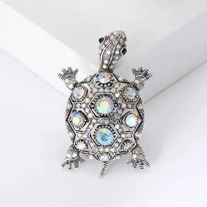 Broche tortue vintage en argent avec strass AB étincelants sur un piédestal blanc épuré