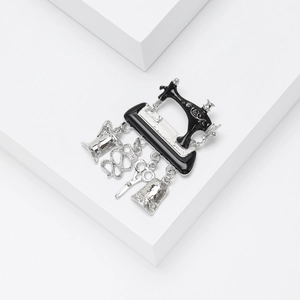 Detail of vintage sewing machine brooch with scissor and button dangling charms