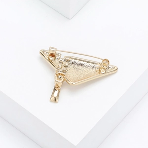 Macro side view of golden triangle brooch with secure safety pin and pendant detail
