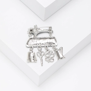Macro shot of silver vintage sewing machine brooch with scissors and button charms
