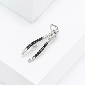 Détail de la broche en forme de pince dentaire avec placage argent et émail noir