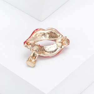 Creative enamel lip brooch with gold plating and safety pin fastening on white background