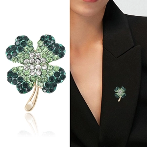 Elegant gold four-leaf clover brooch with green rhinestones and a polished stem