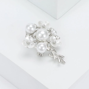 Dettaglio della spilla a fiore argento con eleganti perle bianche e strass lucidi