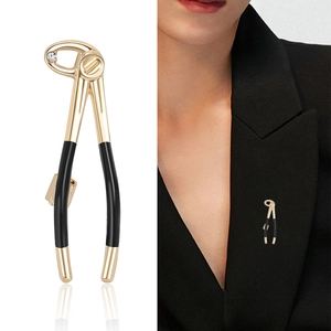 Broche pince dentaire dorée avec manche noir et zircon sur fond blanc pur