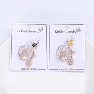 Detail of bee riding bicycle brooches with rhinestones and enamel on white tray
