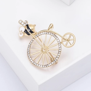 Detail of vintage gold bike brooch with rhinestones, bee element and enamel finish