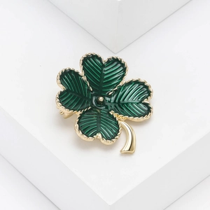 Détail macro d'une broche trèfle à quatre feuilles en émail vert et métal doré de luxe