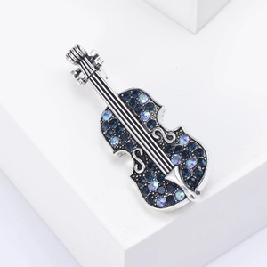 Detailed close-up of retro violin brooch with deep blue rhinestones on white stand