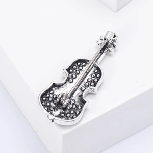 Macro view of retro violin brooch back showing pin clasp and textured silver alloy finish