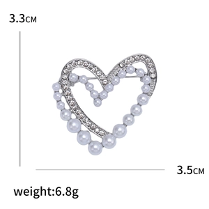 Elegante spilla a forma di cuore con perle e strass e misure su uno sfondo bianco puro
