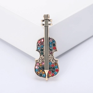 Vintage gold violin brooch for women with colorful rhinestones on a white pedestal
