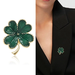Élégante broche trèfle à quatre feuilles en émail vert et doré sur un blazer noir