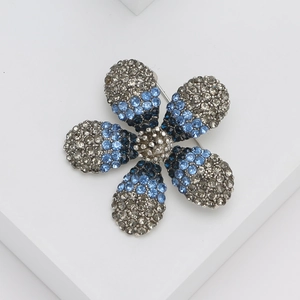 Detailed close-up of crystal flower brooch with gradient blue rhinestones on silver base