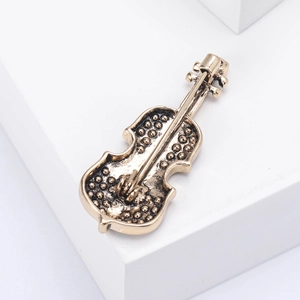 Macro shot of elegant violin brooch in vintage gold finish on a geometric stand