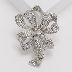 Detail of elegant silver bow brooch with AB rhinestones on minimalist white background