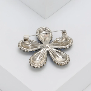 Detail view of the silver-tone metal floral brooch back showing a secure pin clasp