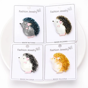 Detail of four colorful hedgehog enamel pins displayed in a white bowl with card packaging