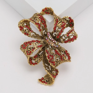 Elegant vintage gold bow brooch with red rhinestones on a minimalist white platform