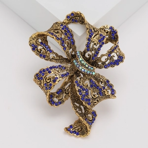 Macro detail of vintage ribbon bow brooch with dark blue rhinestones and antique gold finish