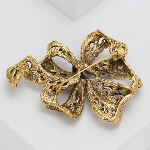 Detail view of the back structure and pin clasp on a vintage gold rhinestone ribbon brooch