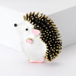 Cute hedgehog enamel brooch pin with gold details and pink accents on a white block