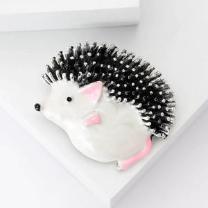 Detailed macro view of the white enamel hedgehog brooch featuring sharp silver-tone spikes