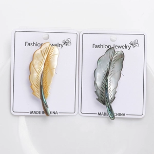 Detailed close-up of shell feather brooches with natural iridescent finish on display