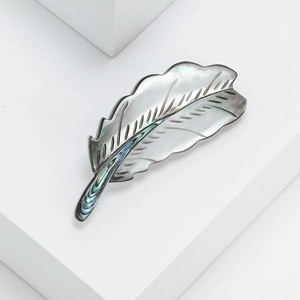 Macro detail of luxury feather brooch with iridescent natural mother of pearl inlay