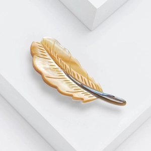 Macro shot of an elegant natural mother of pearl feather brooch with silver metal base