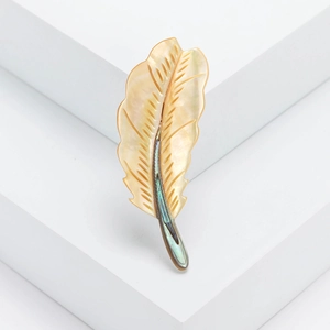 Elegant feather brooch crafted with natural mother of pearl on a white pedestal