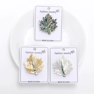 Detailed view of three maple leaf brooches with natural mother of pearl inlay texture