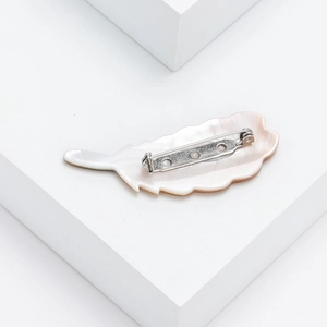 Macro detail of natural mother-of-pearl feather brooch with silver metal safety pin back