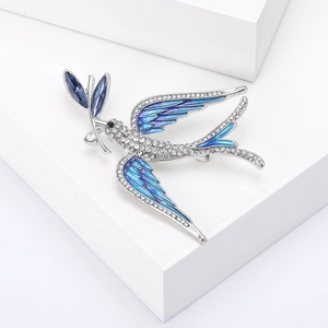 Macro shot of silver bird brooch with blue enamel wings and clear rhinestones detail