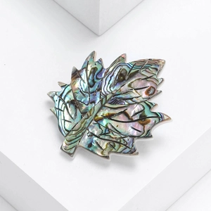 Macro detail of natural abalone shell maple leaf brooch with iridescent luster finish