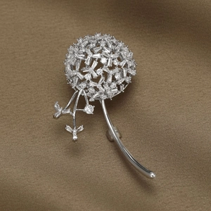 Détail macro d'une broche pissenlit avec zircons sur fond de satin marron chic