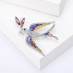 Macro detail of bird brooch with colorful enamel wings and pave-set crystal rhinestones