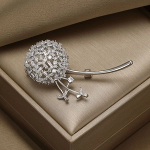 Élégante broche pissenlit en argent avec zircons sur un écrin à bijoux marron