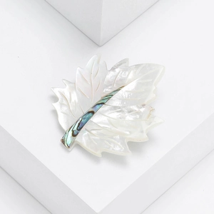 Macro detail of natural mother of pearl maple leaf brooch with abalone shell inlay