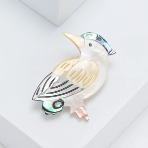 Elegant kingfisher brooch made of natural shell with iridescent finish on white background