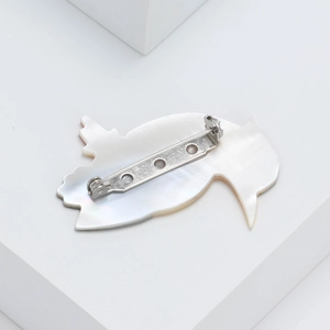 Back view of natural shell parrot brooch with silver pin buckle on white background