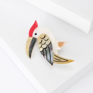 Eleganter Vogel-Brosche aus Naturschale mit roter Krone und Marmortextur auf weißem Stand
