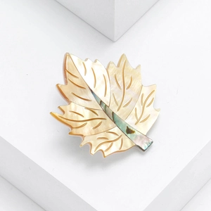 Detailed close-up of natural shell maple leaf brooch with delicate carved veins