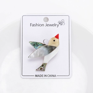 Détail d'une élégante broche oiseau en nacre naturelle sur carte de bijoux