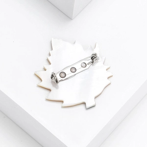 Detailed back view of maple leaf brooch with silver safety pin and white mother of pearl